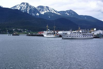 Sailboats in sea by mountains against sky