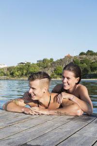 Happy couple enjoying while leaning at lake's pier