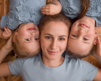 Portrait of smiling mother with girls lying on floor