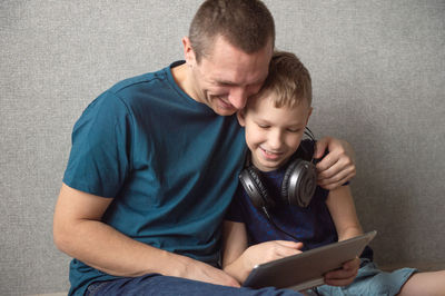 Dad hugs his son tightly. my son is playing on a tablet. large headphones