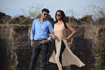 Portrait of happy young couple standing against trees