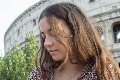 Portrait of young woman standing against building