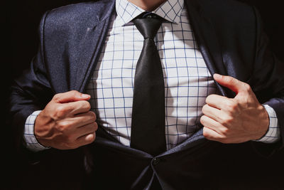 Midsection of businessman with broad shoulder against black background