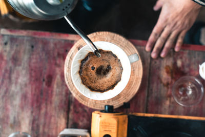 High angle view of coffee pouring in cup on table