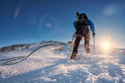 Man on snowcapped mountain against blue sky