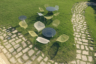 High angle view of tables and chairs in lawn during sunny day