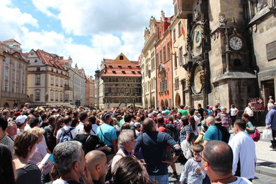 Crowd at town square standing by prague astronomical clock against sky
