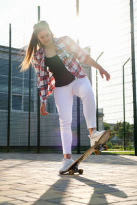 Woman riding a skateboard on street. skater girl on a longboard. cool female skateboarder at sunset. 