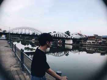 Man standing on bridge over river against sky