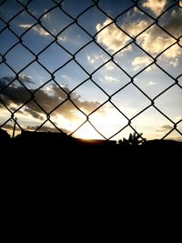 Silhouette fence against sky during sunset