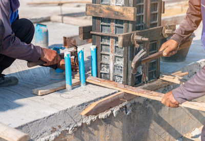 Two workers nailed the wooden sticks to support the concrete framwork pillars