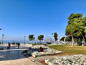 Group of people by the sea against clear blue sky