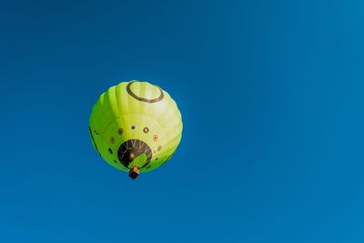 Low angle view of hot air balloon flying against blue sky