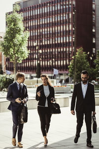 Entrepreneur discussing strategy with male and female colleagues while walking outdoors