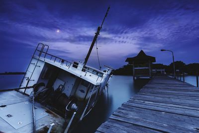 Built structure on pier at sea against sky at dusk