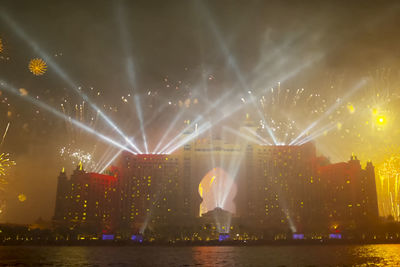 Firework display over illuminated city at night