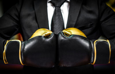 Close-up of midsection of businessman wearing boxing glove