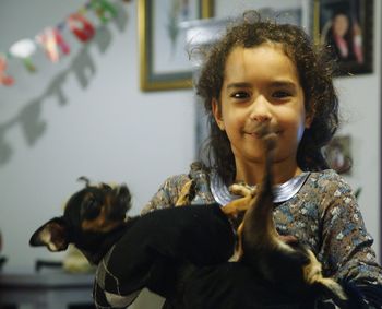 Portrait of smiling girl with dog at home