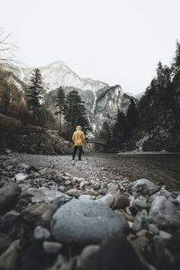 Rear view of man walking on rocks against sky