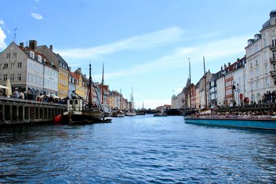 Panoramic view of buildings by river against sky in city