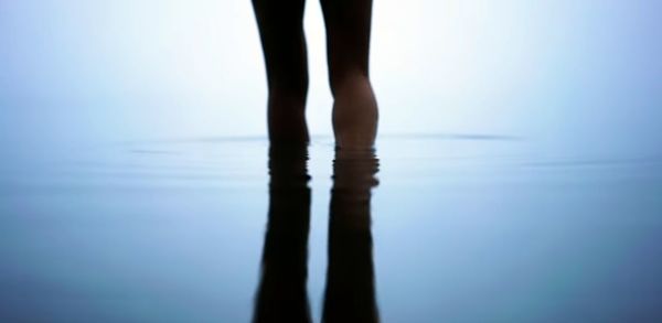 Low section of woman standing in sea