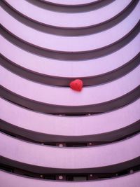 Low angle shot of brutalist pink building with heart shaped umbrella 