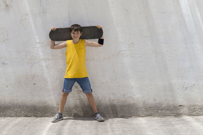 Portrait of smiling boy standing with skateboard
