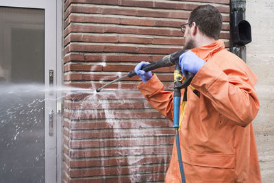 Man cleaning graffiti from wall