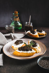 Delicious sandwiches with ricotta and black chia caviar on a plate on the table vertical view