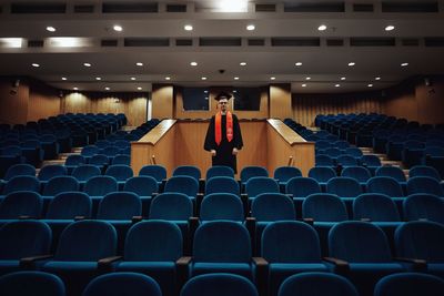 Man standing amidst chair in lecture hall