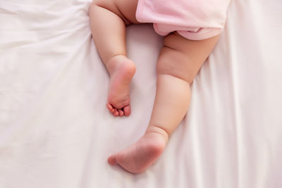 Low section of baby lying on bed