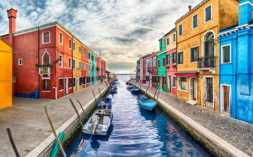 Canal amidst buildings in city against sky