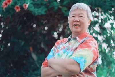 Portrait of happy senior woman standing against trees