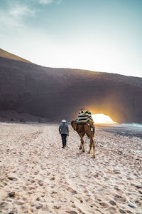 People riding horse on sand against sky