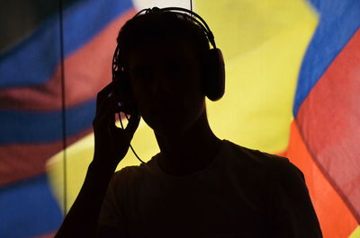 Close-up of silhouette man holding headphones