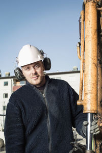 Portrait of confident construction worker holding rod of excavator