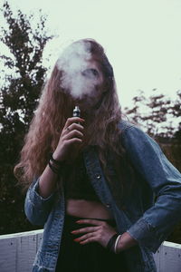 Portrait of young woman smoking outdoors