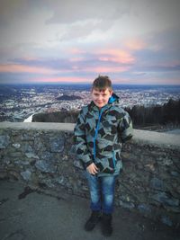 Full length portrait of boy standing on landscape against sky