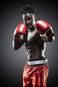 Portrait of shirtless boxer standing against black background