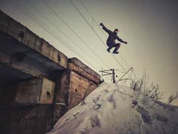 Low angle view of man jumping on snow