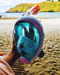 Close-up of hand holding sunglasses on beach