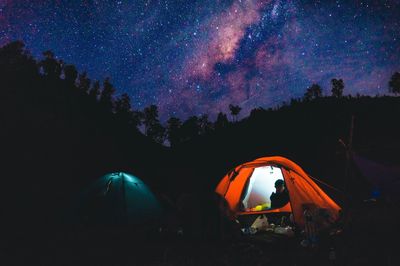 Light trails on illuminated field against sky at night