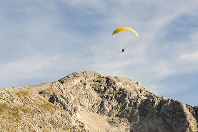 Low angle view of person paragliding against sky