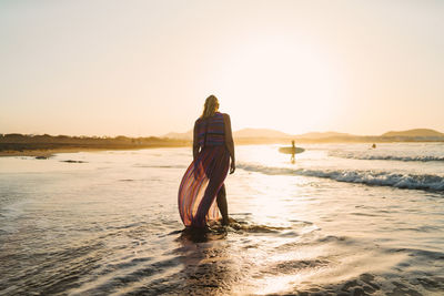 Rear view of woman at beach during sunset