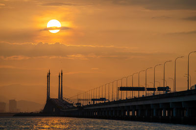 Bridge over sea against sky during sunset