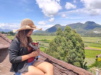 Midsection of woman sitting on mountain against sky