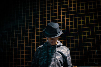 Man wearing hat while standing against fence 