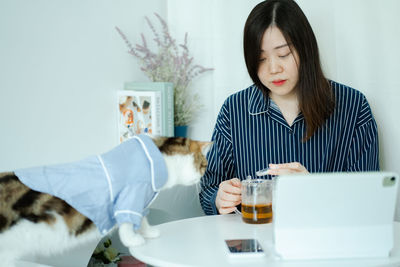 Woman in pajamas cloth drink tea and play with her cat