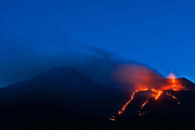 View of volcano erupting at night