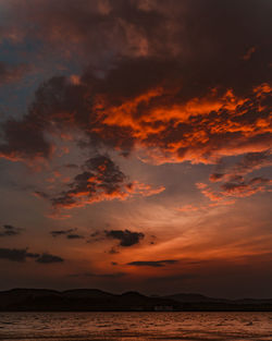 Scenic view of sea against dramatic sky during sunset